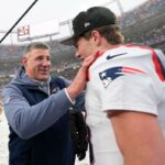 O técnico do New England Patriots, Mike Vrabel, fala com o quarterback Drake Maye após um jogo de futebol americano da NFL com neve.