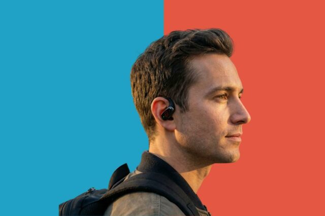 Mulher usando um capacete de ciclismo e um fone de ouvido em um ambiente urbano.