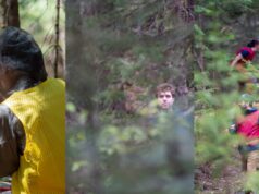 Pesquisadores caçam uns aos outros na região selvagem de Quebec – pela ciência, é claro Um homem sorridente de chapéu e colete vermelho corre por uma área arborizada com um apito na boca