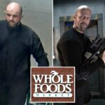 Imagem de vigilância de um homem careca, com barba, vestindo uma camisa preta, carregando um saco de papel marrom e uma sacola de plástico verde.