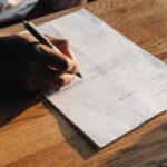 Uma pessoa sentada à mesa preenchendo um documento. Por que o novo limite de relatório de jogos de azar do IRS é importante