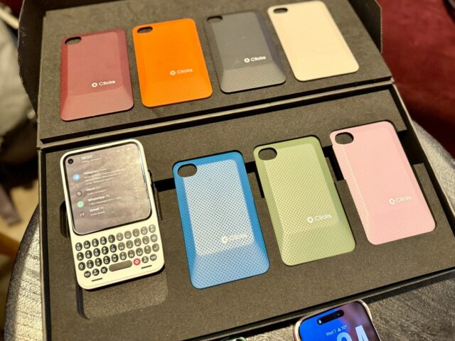 Prática com um protótipo do Clicks' Communicator, um novo smartphone uma foto mostrando o dispositivo Clicks Communicator, com uma concha laranja e um botão de notificação vermelho iluminado na lateral.