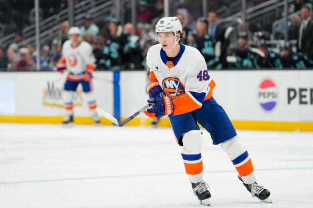 Um jogador nº 48 do New York Islanders, provavelmente Simon Holmstrom, patina com seu taco no gelo durante um jogo contra o Buffalo Sabres.
