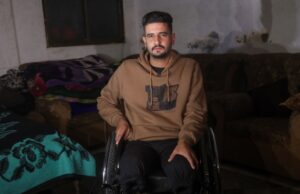Primos de Gaza enfrentam juventude perdida e tragédia familiar após amputações Foto de Abdullah Nattat em pé ao telefone