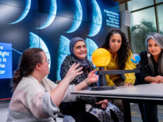 Projeto Moonsighting une ciência e religião Uma foto de Imad Ahmed. Ele é careca, com bigode preto e cinza e cavanhaque. Ele está usando óculos e um lenço cinza.
