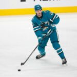 O defensor do San Jose Sharks, Vincent Iorio (22), tenta passar o disco durante o jogo da NHL entre o Vegas Golden Knights e o San Jose Sharks em 11 de janeiro de 2026 no SAP Center em San Jose, CA.