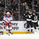 O ala direito do Los Angeles Kings, Adrian Kempe, segundo a partir da direita, comemora seu gol com o ala direito Corey Perry, à direita, enquanto o goleiro do New York Rangers, Jonathan Quick, à esquerda, e o centro JT Miller aguardam durante o primeiro período de um jogo de hóquei da NHL na terça-feira, 20 de janeiro de 2026, em Los Angeles.