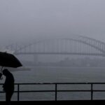 Pessoas são vistas enfrentando a chuva e a neblina na cadeira da Sra. Macquaries esta manhã, sexta-feira, 22 de agosto de 2025. Após semanas de chuva persistente, partes da costa de NSW registraram o agosto mais chuvoso em 126 anos. Foto: Sam Mooy / The Sydney Morning Herald