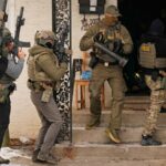 Um oficial do ICE usa spray de pimenta em um manifestante enquanto os agentes se preparam para fazer uma prisão no domingo.