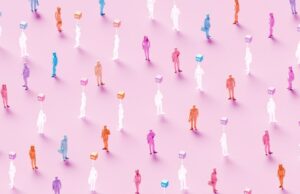 Os agentes de IA estão prontos para o local de trabalho? Um novo benchmark levanta dúvidas. 3D rendered conceptual illustration of numerous business figures evenly scattered across a soft pink background: solid colored human workers standing alongside identical translucent ghost-like figures, each translucent worker marked by a glowing “AI” symbol hovering above – powerful visualization of artificial intelligence replacing human workforce, solid employees mixed with their AI-replaced counterparts, automation displacing jobs, digital transformation eliminating roles, technological unemployment, workforce disruption, future of work with AI substitution, and the new era where real human workers are gradually replaced by artificial intelligence.