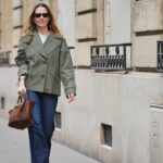 NOVA IORQUE, NOVA IORQUE - 14 DE FEVEREIRO: Um convidado usa cabelo trançado, brincos, colar, anéis de ouro, uma bolsa clutch de cetim rosa, um vestido branco com decote em V, gravata na cintura e estampa floral, sandálias douradas metálicas abertas, fora de Altuzarra, durante a New York Fashion Week, em 14 de fevereiro de 2026 na cidade de Nova York (Foto de Edward Berthelot / Getty Images)