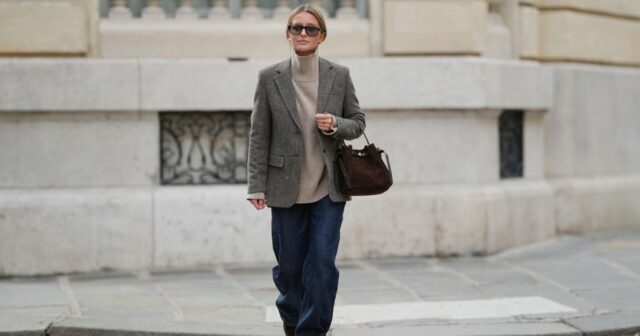 Laura Noltemeyer é vista vestindo um suéter cinza de malha fina com gola frontal drapeada escultural da Zara; jeans de perna reta azul claro com desbotamento suave da Zara; botas de inverno em camurça bege com bico arredondado, atacadores de corda, costura tonal e sola de borracha grossa da Inuikii; uma grande bolsa de ombro marrom escuro texturizada em um formato escultural suave e desleixado e couro tecido da Les Visionnaires x Michi da Want; óculos de sol ovais pretos com armação em acetato brilhante e lentes escuras da Celine; brincos esculturais de ouro grossos da Zara; luvas de couro macio marrom escuro da Zara; seu cabelo castanho escuro está liso com uma divisão ao meio, preso atrás das orelhas em 25 de novembro de 2025 em Berlim, Alemanha.