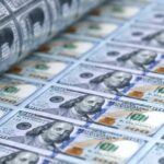 Notas de cem dólares saindo de uma impressora.