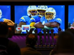 A NFL pode estar caminhando para expandir o relacionamento com o YouTube para transmissões de jogos Dois homens assistindo a um jogo da NFL transmitido no YouTube TV em várias telas de um bar.