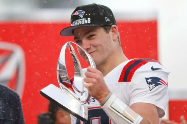 Drake Maye comemora com o troféu Lamar Hunt após a vitória dos Patriots sobre os Broncos no Campeonato AFC.