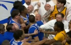 A briga VCU-Saint Louis começa após um movimento de coçar a cabeça na campainha Um jogador de basquete com camisa azul é afastado de um jogador adversário com camisa amarela, enquanto treinadores e outros jogadores tentam acalmar a situação.