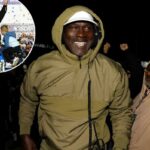 Michael Jordan com uma jaqueta com capuz e boné branco sorrindo após a vitória de Tyler Reddick na NASCAR Cup Series.