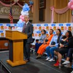 A vereadora da cidade de Oakland, Janani Ramachandran, segura seu filho Nilaan, de 1 ano, enquanto participava de uma coletiva de imprensa comemorando o lançamento de