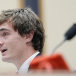 Nick Shirley fala durante uma mesa redonda com o presidente Donald Trump sobre antifa no State Dining Room da Casa Branca, quarta-feira, 8 de outubro de 2025, em Washington, enquanto Savanah Hernandez ouve. (Foto AP/Evan Vucci)