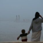 uma foto de um menino sorrindo para a câmera em uma camiseta verde