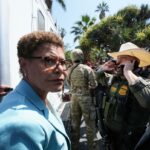 A prefeita de Los Angeles, Karen Bass, falando em um pódio com o selo da cidade.