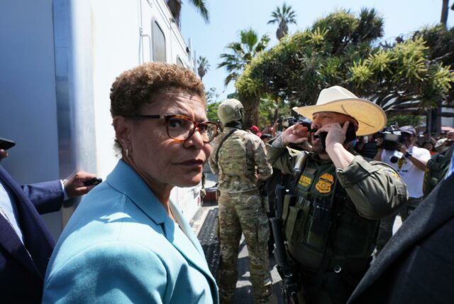 A prefeita de Los Angeles, Karen Bass, falando em um pódio com o selo da cidade.
