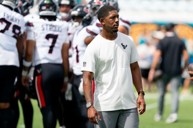 O técnico assistente dos linebackers do Houston Texans, Ben Bolling, assiste ao aquecimento antes de um jogo da NFL 