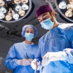 Stock image: Medical professionals performing surgery in a modern operating room, illuminated by bright overhead lights.
