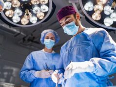 Alerta médico emitido sobre cirurgia de transição de gênero para crianças Stock image: Medical professionals performing surgery in a modern operating room, illuminated by bright overhead lights.