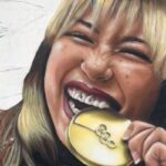 Alysa Liu mordendo sua medalha de ouro na Cerimônia de Vitória da Patinação Individual Feminina.