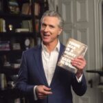 Gavin Newsom segurando seu livro,