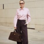 PARIS, FRANÇA - 12 DE JANEIRO: Maria Rosaria Rizzo usa longos cabelos castanhos soltos e repartidos ao centro, óculos de sol Saint Laurent com lentes escuras, uma bolsa Pinel et Pinel preta e branca com formato retangular estruturado em couro com logotipo do monograma impresso e alças superiores duplas transportadas à mão, um suéter de malha Marella preto com decote redondo, uma jaqueta Akep cortada em um padrão texturizado preto e branco com lapelas largas e fecho de botão frontal usado sobre os ombros, preto Calça de alfaiataria Balmain com perna reta, sapatilhas de couro preto Salvatore Ferragamo com bico arredondado, detalhe dourado e sola discreta, durante sessão de fotos de moda street style, no dia 12 de janeiro de 2026 em Paris, França. (Foto de Edward Berthelot/Getty Images)