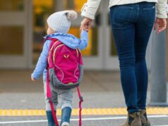 Australianos com bom dinheiro estão sendo excluídos da paternidade Vista traseira de uma jovem mãe alegre segurando a mão da filha enquanto caminhava na faixa de pedestres até a escola da criança.
