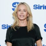 Chelsea Handler sorrindo na frente de um fundo branco com logotipos SiriusXM azuis.