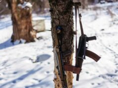 Cidadão dos EUA condenado a quatro anos de prisão na Rússia após tentar contrabandear estoques de rifles de assalto Kalashnikov para fora do aeroporto de Moscou: relatórios Dois rifles de assalto Kalashnikov pendurados em uma árvore em uma paisagem nevada.