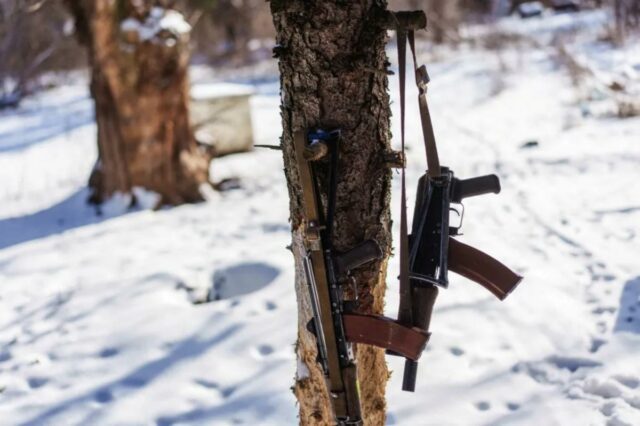 Cidadão dos EUA condenado a quatro anos de prisão na Dois rifles de assalto Kalashnikov pendurados em uma árvore em uma paisagem nevada.