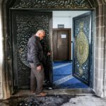 Um homem inspeciona pichações hebraicas ofensivas nas paredes do lado de fora da mesquita Abu Bakr al-Siddiq, na vila de Tell, a oeste de Nablus, na Cisjordânia ocupada, em 23 de fevereiro de 2026, após um suposto ataque de colonos israelenses.