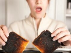Comida queimada é realmente tão ruim para você? Os riscos reais – e como evitá-los Uma mulher com a boca aberta de surpresa segura duas fatias de torrada queimada em uma torradeira.