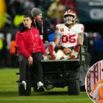Um jogador de futebol sendo retirado do campo sentado ao lado de um membro da equipe médica.