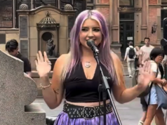 Conselho de Sydney dá meia-volta na ‘proibição’ divisiva após reclamações Uma jovem de cabelo roxo canta em um microfone enquanto toca na George Street, em Sydney. Ela está vestindo uma blusa preta e saia roxa.