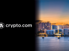 Crypto.com enfrenta processo na Flórida por supostas apostas esportivas ilegais Logotipo e nome da Crypto.com em branco sobre fundo preto ao lado do horizonte de uma cidade à beira-mar ao pôr do sol com arranha-céus iluminados e barcos em águas calmas. Crypto.com enfrenta processo na Flórida por supostas apostas esportivas ilegais