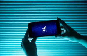 Engenheiros seniores, incluindo cofundadores, saem da xAI em meio a polêmica A person holds a telephone displaying the logo of Elon Musk s artificial intelligence grok in front of a background lit by a blue light.