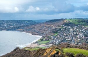 Enorme deslizamento de terra fecha parte do Caminho Costeiro do Sudoeste: Milhares de toneladas de rocha caem na praia de Dorset semanas depois que uma rachadura de 300 pés de comprimento apareceu no topo do penhasco Uma vista aérea de um deslizamento de terra em andamento em Stonebarrow Hill em Charmouth, em Dorset, que fechou o Caminho da Costa Sudoeste
