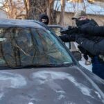 Agentes do governo dos EUA mantêm dois manifestantes sob a mira de uma arma em Minneapolis.