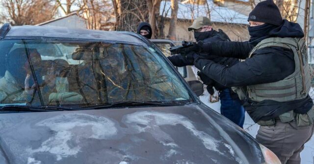 Agentes do governo dos EUA mantêm dois manifestantes sob a mira de uma arma em Minneapolis.