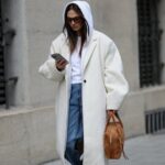 PARIS, FRANÇA - 05 DE MARÇO: Yoyo Cao usa um pulôver de gola alta de lã com nervuras laranja, uma jaqueta de couro marrom brilhante / tiras de couro preto / mangas acolchoadas com zíper, calças grandes verdes de veludo com nervuras, fora da Hermes, durante a Paris Fashion Week - Moda Feminina F/W 2022-2023, em 05 de março de 2022 em Paris, França. (Foto de Edward Berthelot/Getty Images)