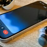 Caixa aberta do Google Pixel Buds Pro 2 com botões de peônia na mesa cercada por granulados