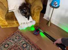 Experimentei o novo PencilVac da Dyson, um aspirador de pó com metade do peso e o dobro dos lasers. Não, não vou relaxar. Dyson PencilVac no suporte de carregamento entre o aparador e a poltrona