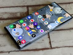 Finalmente encontrei o aplicativo de anotações perfeito depois de anos alternando Um homem parado ao lado de um smartphone gigante com um balde e um esfregão em um fundo azul.