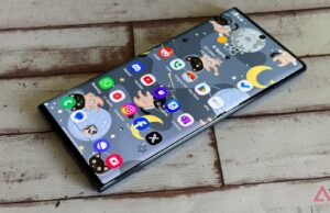 Finalmente encontrei o aplicativo de anotações perfeito depois de anos alternando Um homem parado ao lado de um smartphone gigante com um balde e um esfregão em um fundo azul.